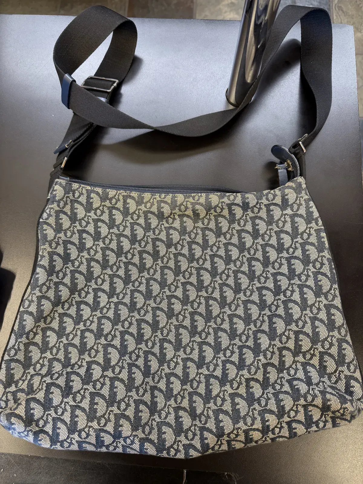 Vintage Dior Trotter navy canvas messenger bag at intake at Baroni Cleaners, a dark grey band of soiling across the jacquard just below the zipper