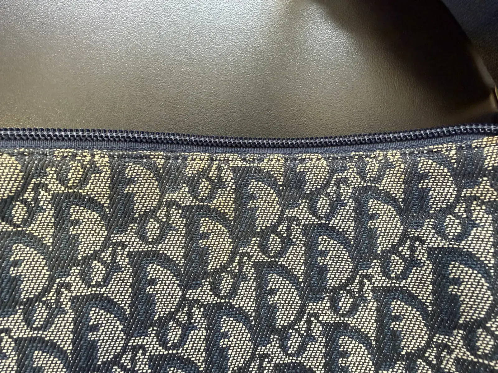 Close-up of the Dior Trotter jacquard before cleaning, body oil and grime sitting in the ecru yarns right under the zipper tape