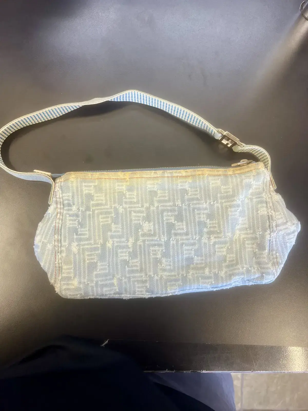Fendi Zucca distressed denim shoulder bag before cleaning at Baroni Cleaners, pale blue denim yellowed along the top zipper edge and dingy across the frayed FF logo pile
