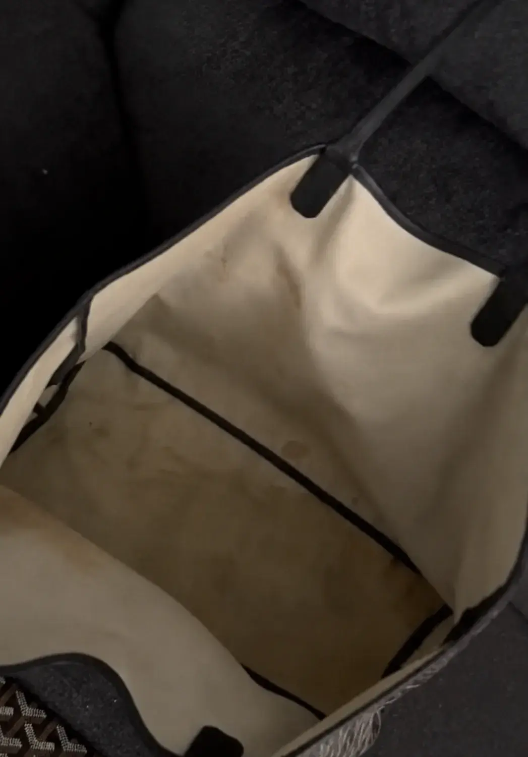 Interior of a Goyard Saint Louis tote before cleaning, cream canvas lining stained brown by spilled makeup