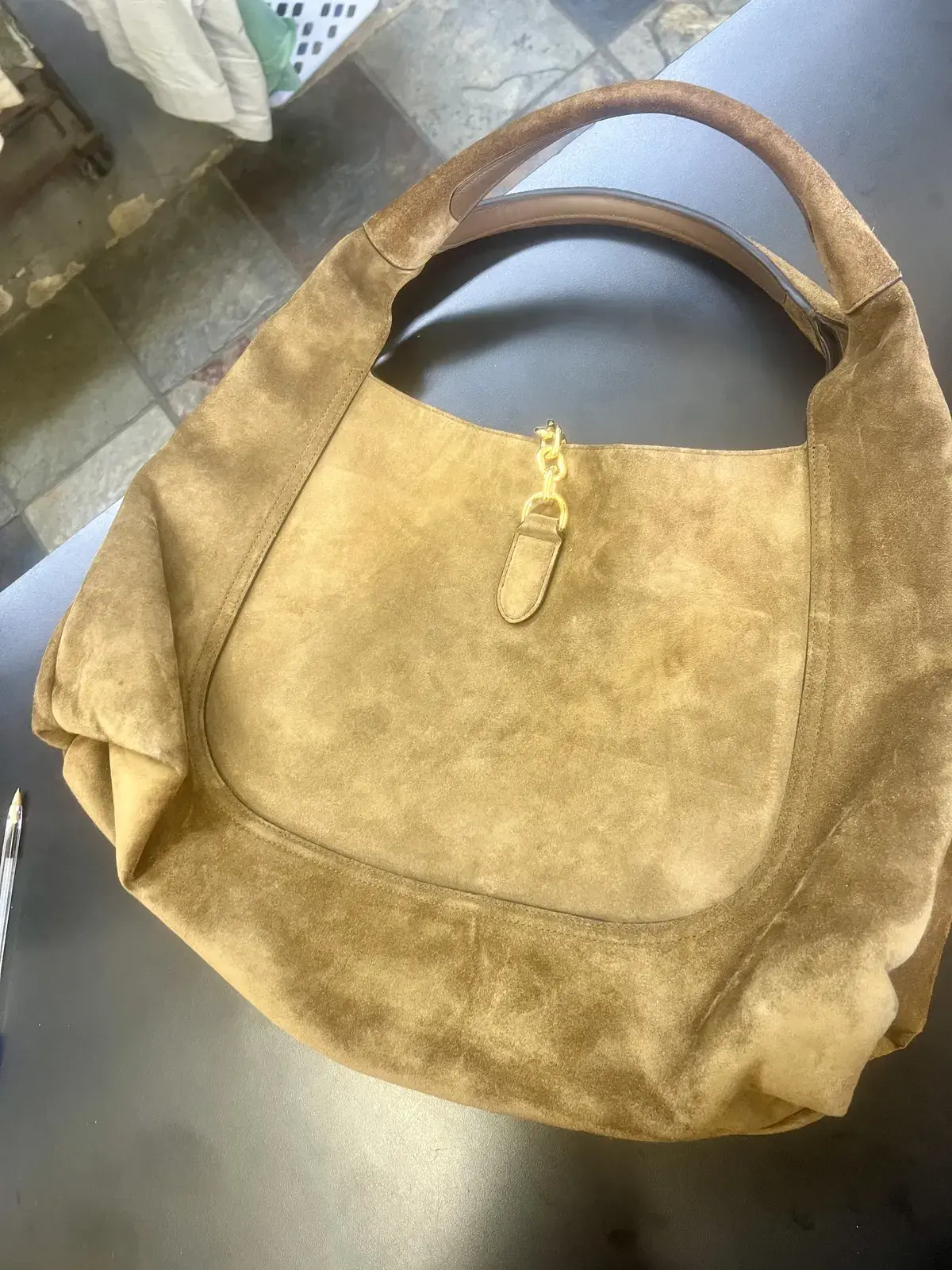 Back of the Gucci suede hobo at intake, patchy oil marks and matted nap across the lower panel below the gold chain tab