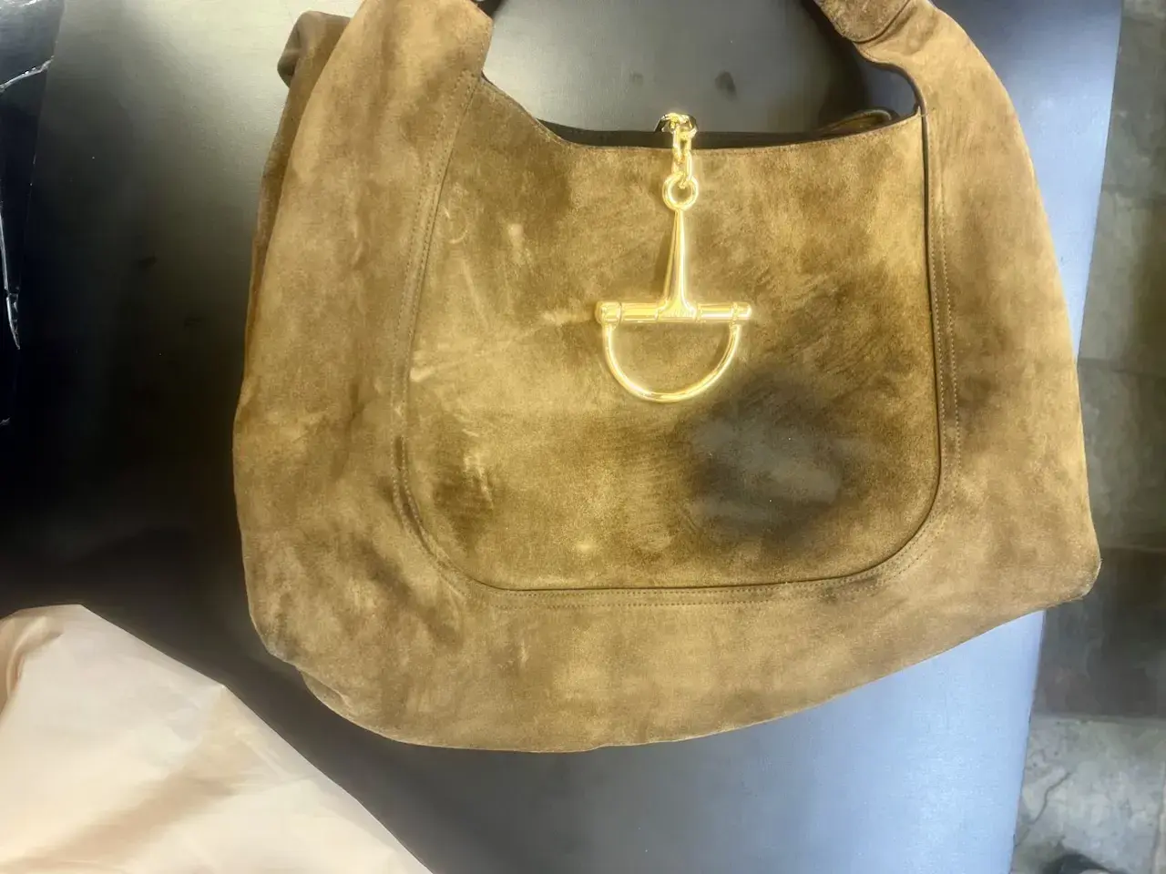 Gucci brown suede hobo bag before cleaning at Baroni Cleaners, dark oil stains blotched across the front panel around the oversized gold horsebit