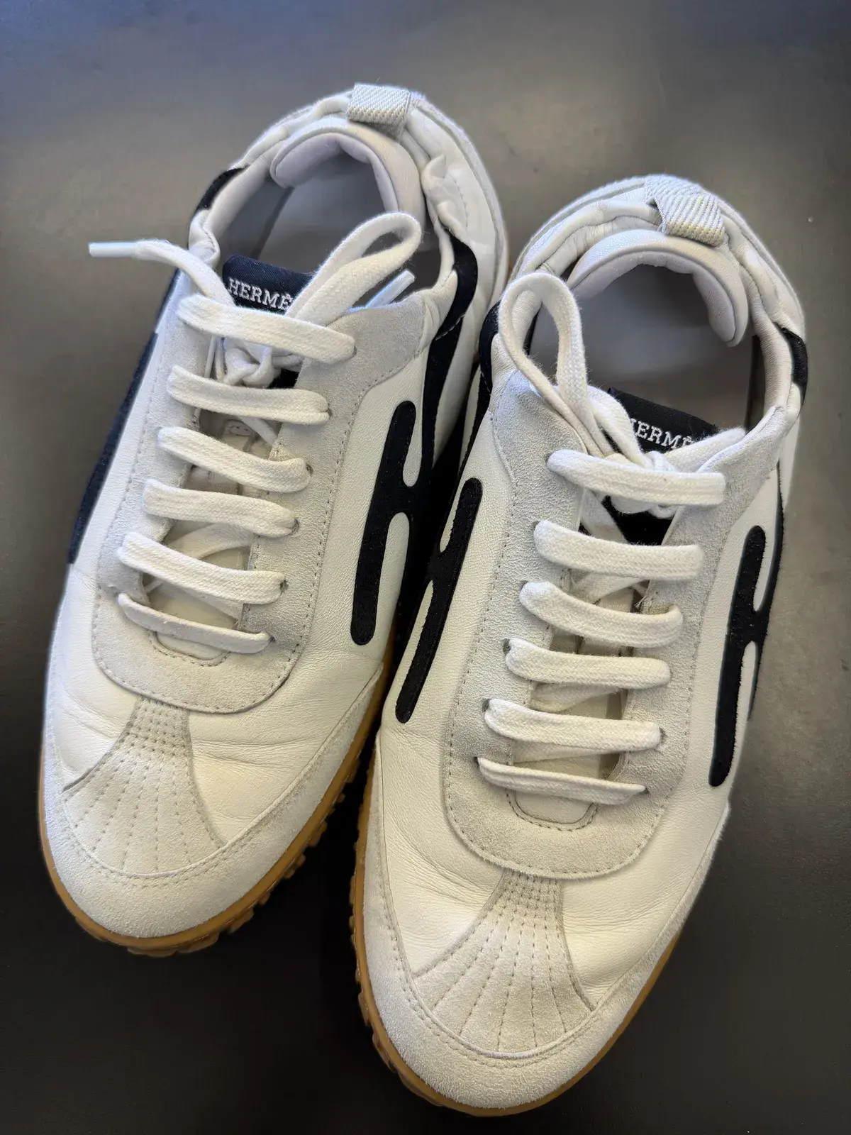 Top-down detail of the cleaned Hermes sneakers, white leather and suede overlays even in tone again