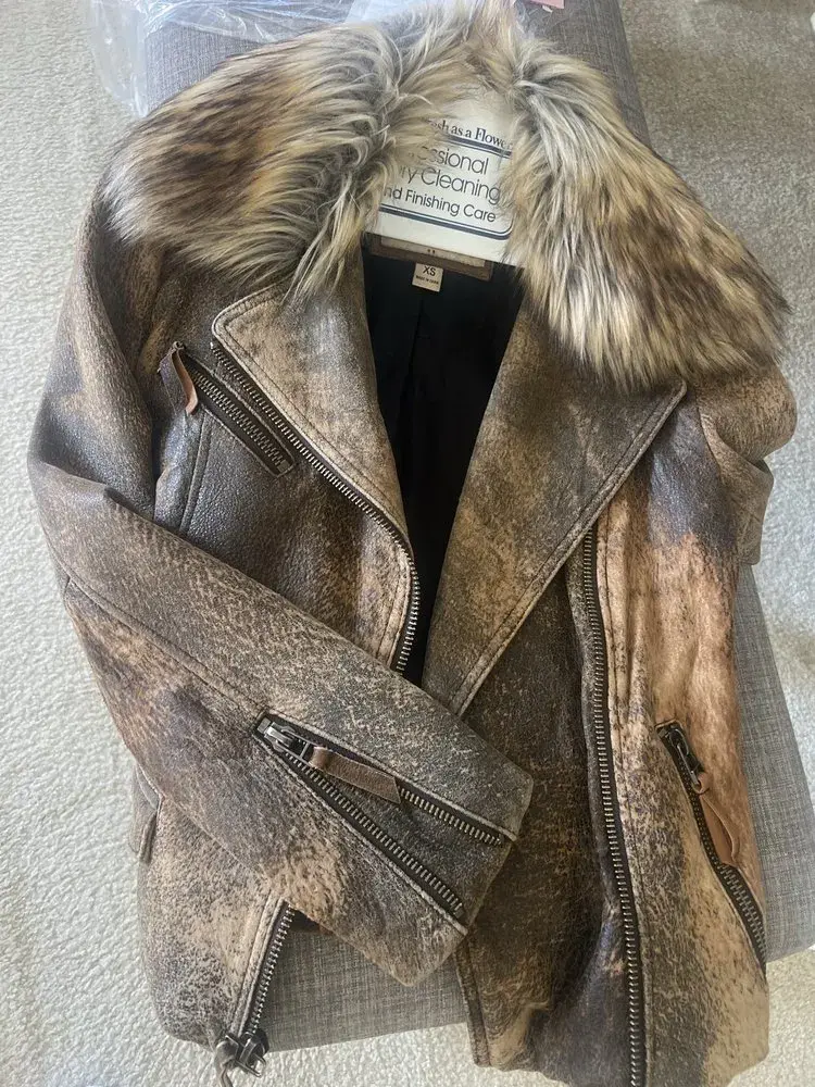 Brown distressed leather moto jacket with a plush fur collar after cleaning and conditioning at Baroni Cleaners Irvine, the two-tone crackle finish even from dark brown to tan and the collar full and soft, photographed by the customer in its delivery bag