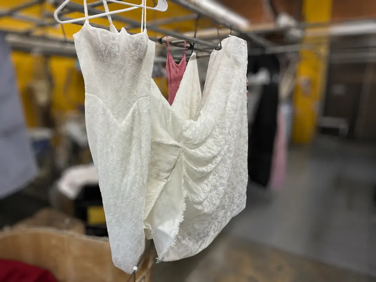 Chantilly lace wedding gown hanging clean and bright after professional wedding dress cleaning at Baroni Cleaners Irvine