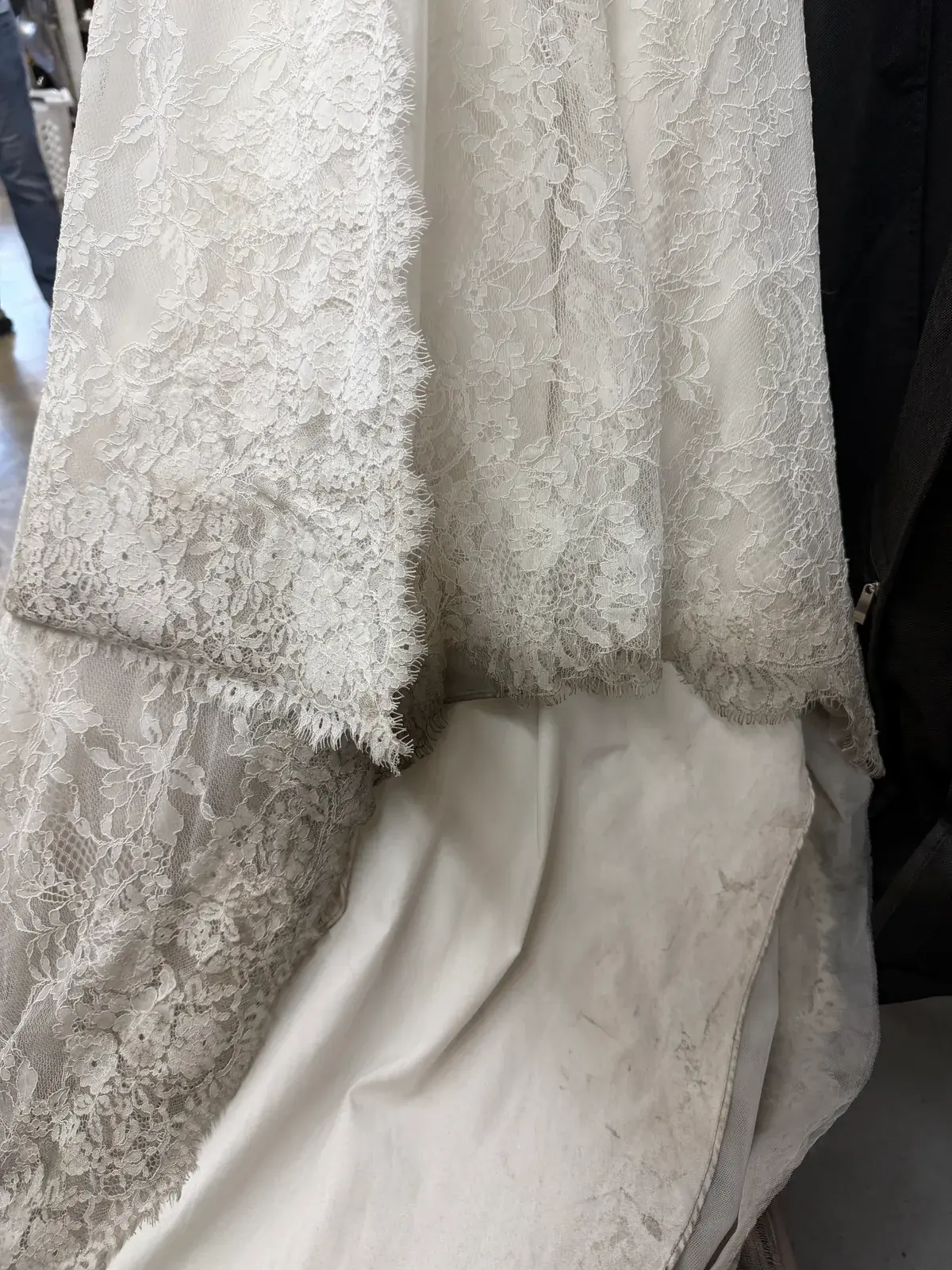 Soiled hem and scalloped lace edge on a Chantilly lace wedding gown before cleaning at Baroni Cleaners Irvine